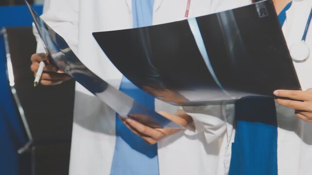 Medical professionals working together at an office desk, discussing information on a laptop, a male doctor pointing at the screen while holding a digital tablet