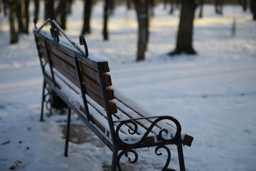 Naklejka premium park bench on a winter alley at snowfall. bench with snow after snowstorm or in snow calamity in europe
