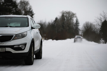 Naklejka premium Winter Road with Snow-Covered SUVs in Forested Countryside