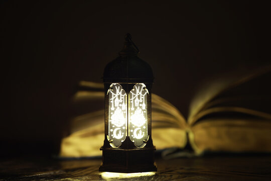 Ornamental Arabic lantern with burning candle glowing at night. Festive greeting card, invitation for Muslim holy month Ramadan Kareem.