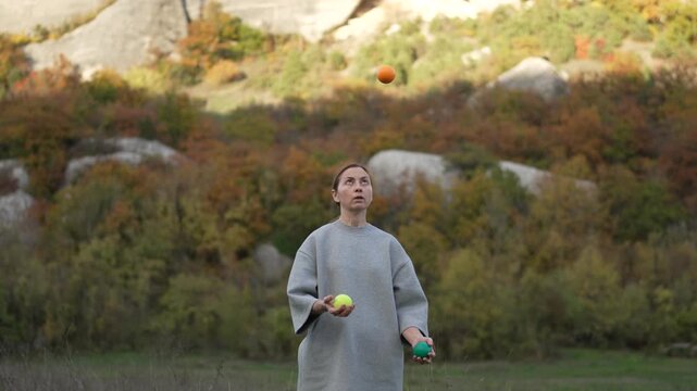 Skilled Juggling Performance Practicing Woman Throws Balls Against Autumn Mountain Backdrop