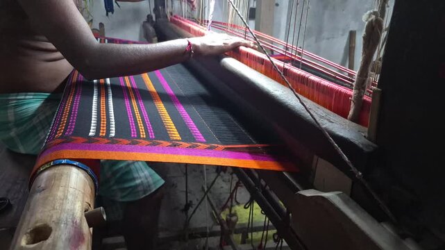 4k 120 fps slow motion video of a  handloom weaver in India working in his loom.	