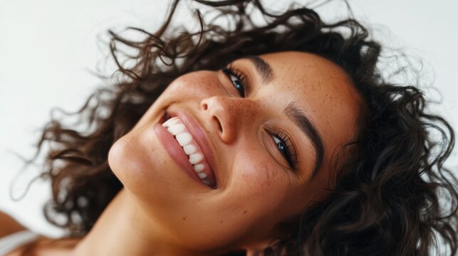 Closeup smiling young woman portrait with curly hair and freckles on white background for wellness banner and natural beauty advertising