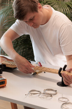 Man carefully cleaning an electric bass guitar fretboard at home
