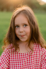 Fototapeta premium little girl runs in a field on the grass at sunset in summer