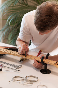 Young man applying care product to an electric bass fretboard