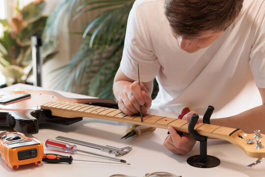 Technician treating a bass guitar fretboard during professional maintenance