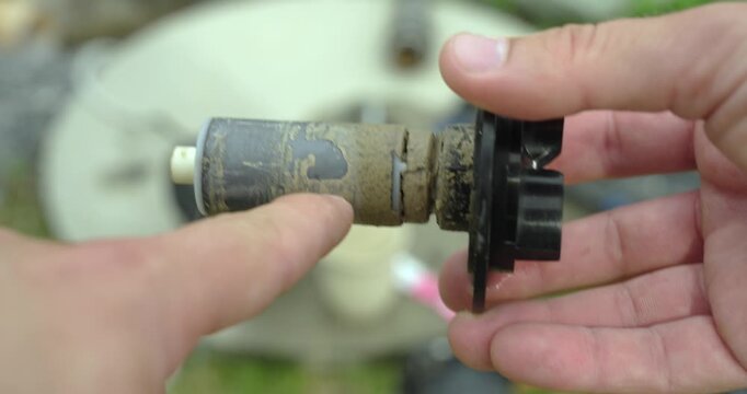 Close-up of a pump rotor with heavy limescale deposits while a person points at the buildup. Maintenance concept of hard water damage, descaling, inspection, and pump repair.
