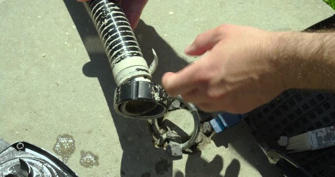Close-up of a person pointing at limescale deposits inside a pump pipe during maintenance. Concept of hard water damage, inspection, descaling, and pump repair.