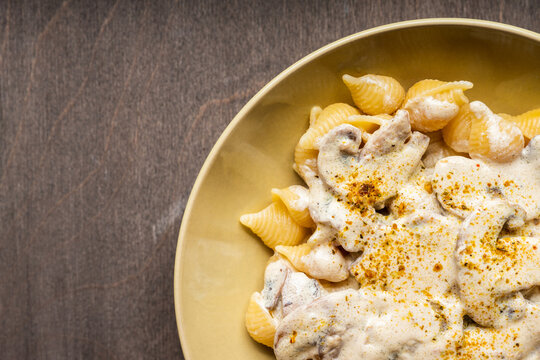 Homemade pasta with creamy mushroom sauce on dark wooden background. Shot from above.