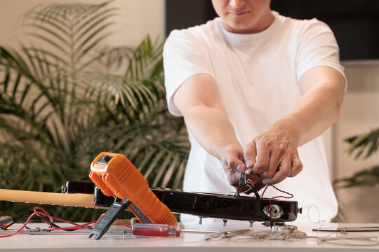 Technician repairing the open electronics compartment of a bass guitar