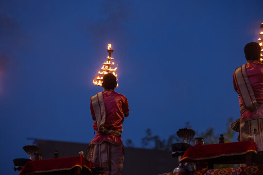 Ganga aarti, Portrait of an young unidentified male priest performing holy river ganga early morning aarti at assi ghat in traditional dress with hindu rituals.