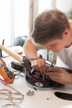 Technician using multimeter probes inside an electric bass guitar