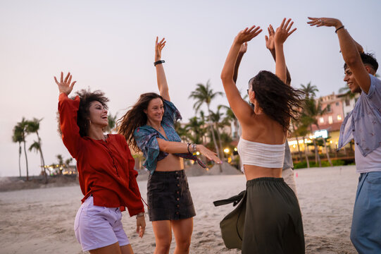 Diverse and multicultural friends dancing on the beach during a summer trip, celebrating friendship