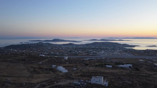 Mykonos Airport at sunset revealing runway, white houses, Aegean Sea with many islands of Cyclades, Greece, offering unique travel and tourism destination