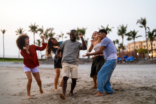 Joyful summer beach party with multiethnic friends celebrating vacation, enjoying music, freedom