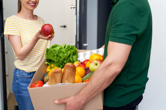 Woman checking fruit while standing with deliveryman at doorway
