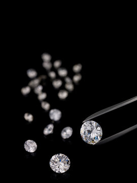 Tweezer holding a sparkling diamond against a black background