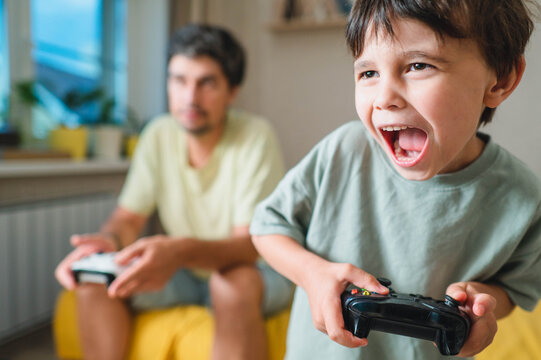 Excited boy plays video games with his father at home