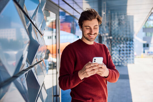 Pedestrian using a smartphone and smiling outdoors