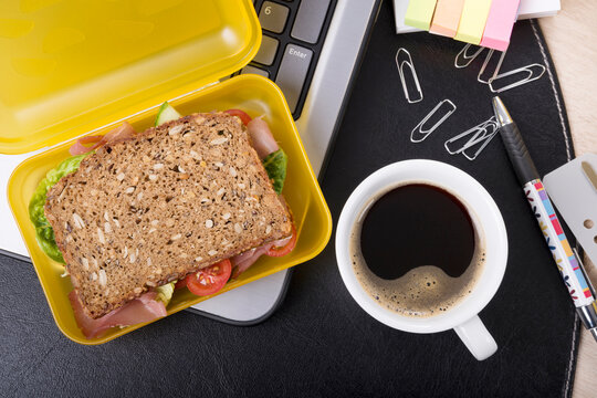 A healthy ham sandwich and coffee sit on an office desk