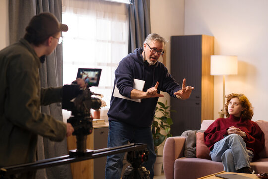 Film director framing a shot with camera operator and actress on set