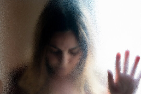 Portrait of mature woman with eyes closed behind glass pane