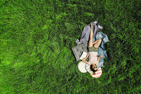 Top view of relaxed woman with book lying on a meadow