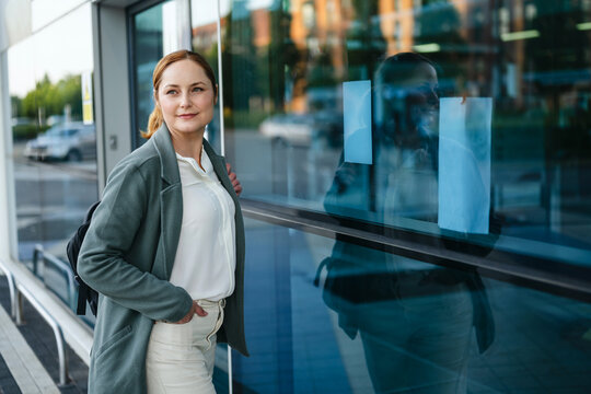 Businesswoman with backpack waiting by a modern glass building