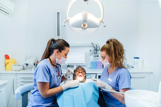 Female dentist and assistent attending patient in medical practice