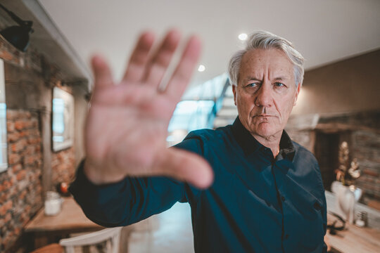 Senior man doing stop gesture in cafe