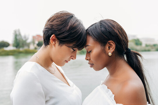 Lesbian couple with eyes closed standing by lake