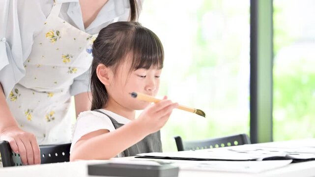 書道に集中して筆で文字を書く小学生の女の子・習字を学ぶ日本の子ども　真剣な表情で先生に教わる動画