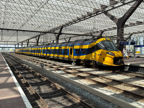 NS Intercity train beneath glass roof at Rotterdam Centraal station in Netherlands