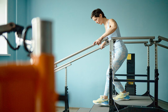 Woman performs rehabilitation exercises on equipment indoors