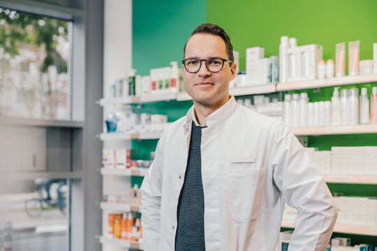 Smiling pharmacist wearing lab coat while standing in chemist shop
