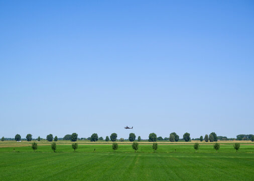 Attack helicopter flying low over a green field in the Netherlands