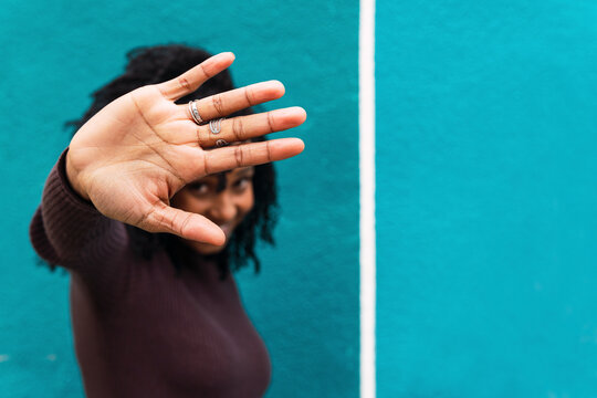 Woman gesturing stop sign in front of blue wall
