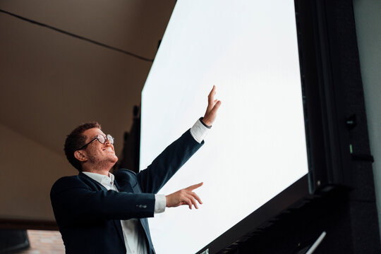 Smiling businessman pointing at blank touchscreen in the office