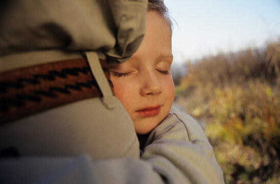 Person resting head on someone in a comforting hug outdoors