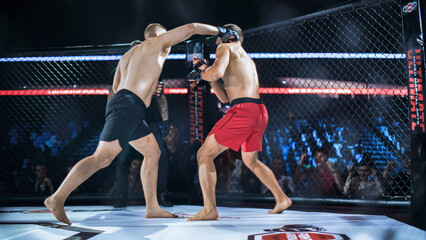 Fototapeta premium MMA Championship Title Belt Fight Action as Two Fighters Trade Punch and Strike Inside the Octagon Cage, One Attacking With a Looping Hook While Opponent Guards, Referee Nearby, Crowd Cheering