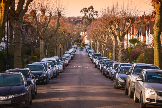 Sunset at a street of terraced houses lined with parked  cars in Crouch End, London, UK