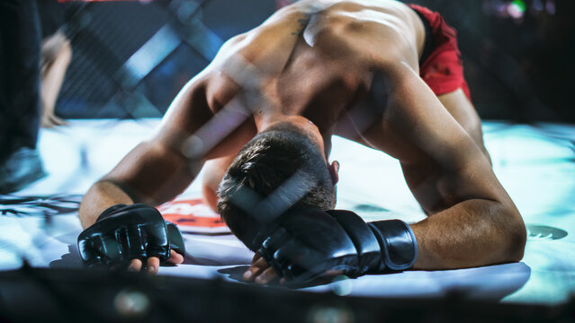 MMA Fighters End a Tough Fight on the Mat as One Drops Face Down After the Final Exchange. Fighter Kneels Nearby, Raw Combat Sport Finish for Match Coverage and Fight for the Champion Title Belt.