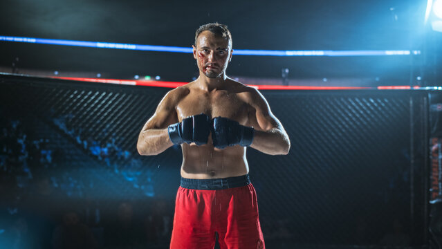 MMA Fighters Continue a Tough Fight Inside the Cage. a Bloodied Fighter Keeps His Guard up and Stays Calm Under Pressure, Grit, Strength in a Competitive Fight for the Champion Title Belt