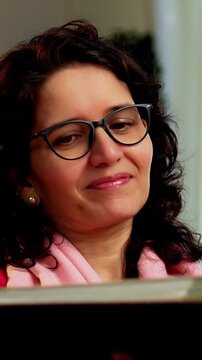 Closeup portrait of a happy Indian Asian pretty young girl in her twenties and her mother in fifties, both looking at the camera while sitting close together on a cozy sofa at home, enjoying their tim
