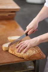 Close up of baker cutting rustic artisan bread with a kitchen knife © uv_group