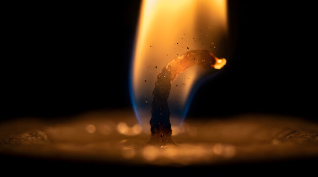 Extreme macro of single candle flame glowing warmly against soft dark background, comfort and warmth connection concept