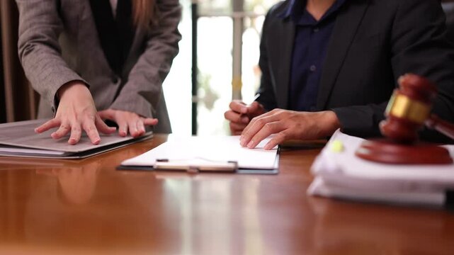 A lawyer providing legal counsel to a client, with detailed documents laid out on the desk and a judge's gavel nearby, symbolizing professionalism, legal consultation, and the judicial process.