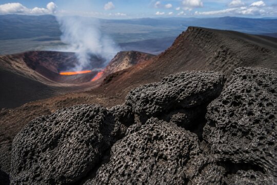 Porous black volcanic scoria at a crater's edge, textured surface.