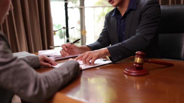 A lawyer providing legal counsel to a client, with detailed documents laid out on the desk and a judge's gavel nearby, symbolizing professionalism, legal consultation, and the judicial process.